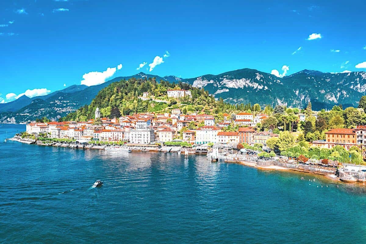 A drone view across water looking towards a small town set amongst mountain scenery on a lake