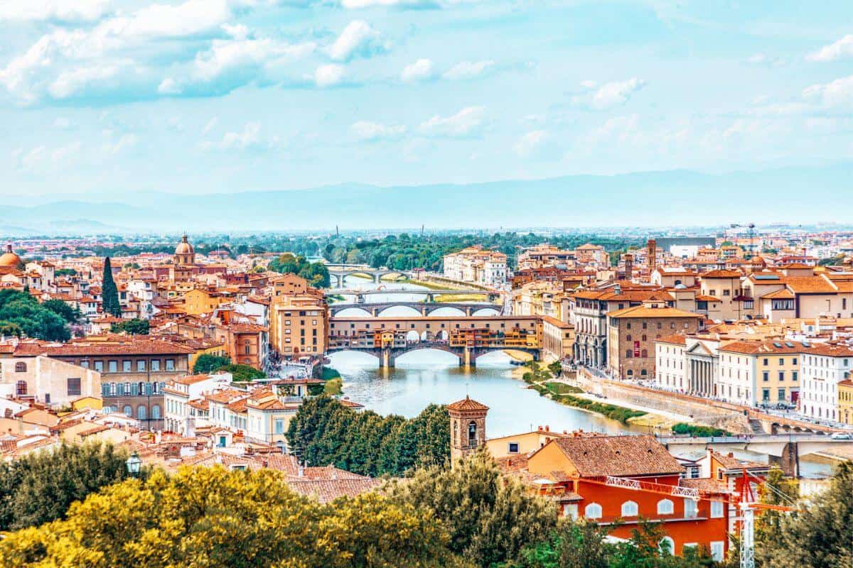 A cityscape with a maze of old buildings and several bridges crossing a grand river