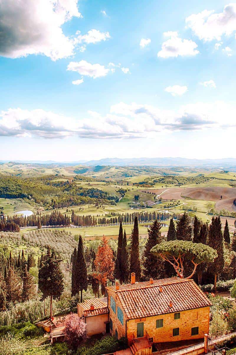 Rural scenery in Italy with green rolling landscapes and a farmhouse in the foreground