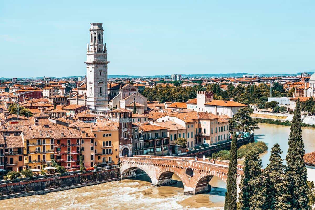 Traditional Italian buildings alongside a wide river and old bridge in Verona