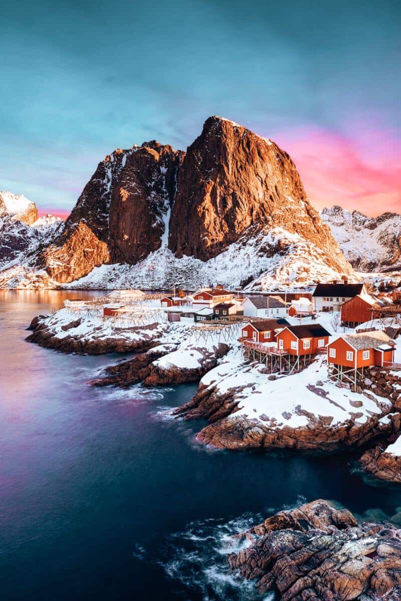 A remote, snowy village in Norway, set against a rugged mountainous backdrop