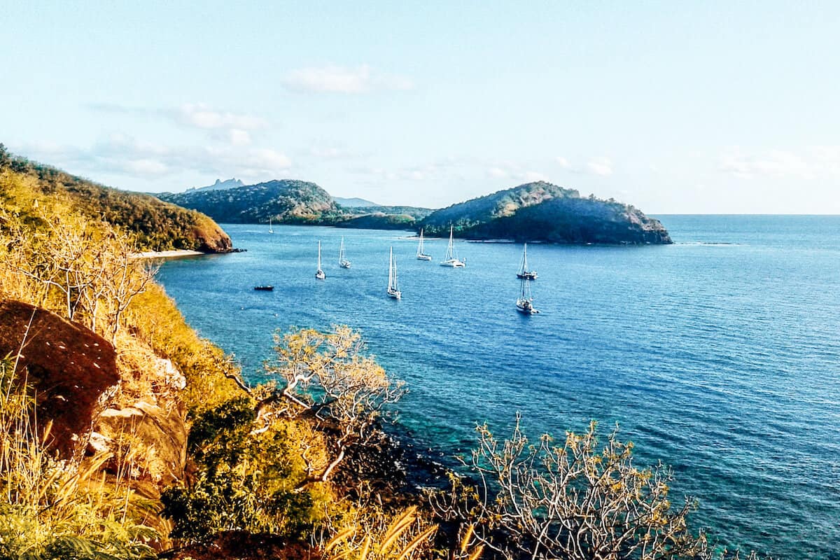 A view from the top of a hill on an island in Fiji overlooking neighbouring islands and small sailing boats