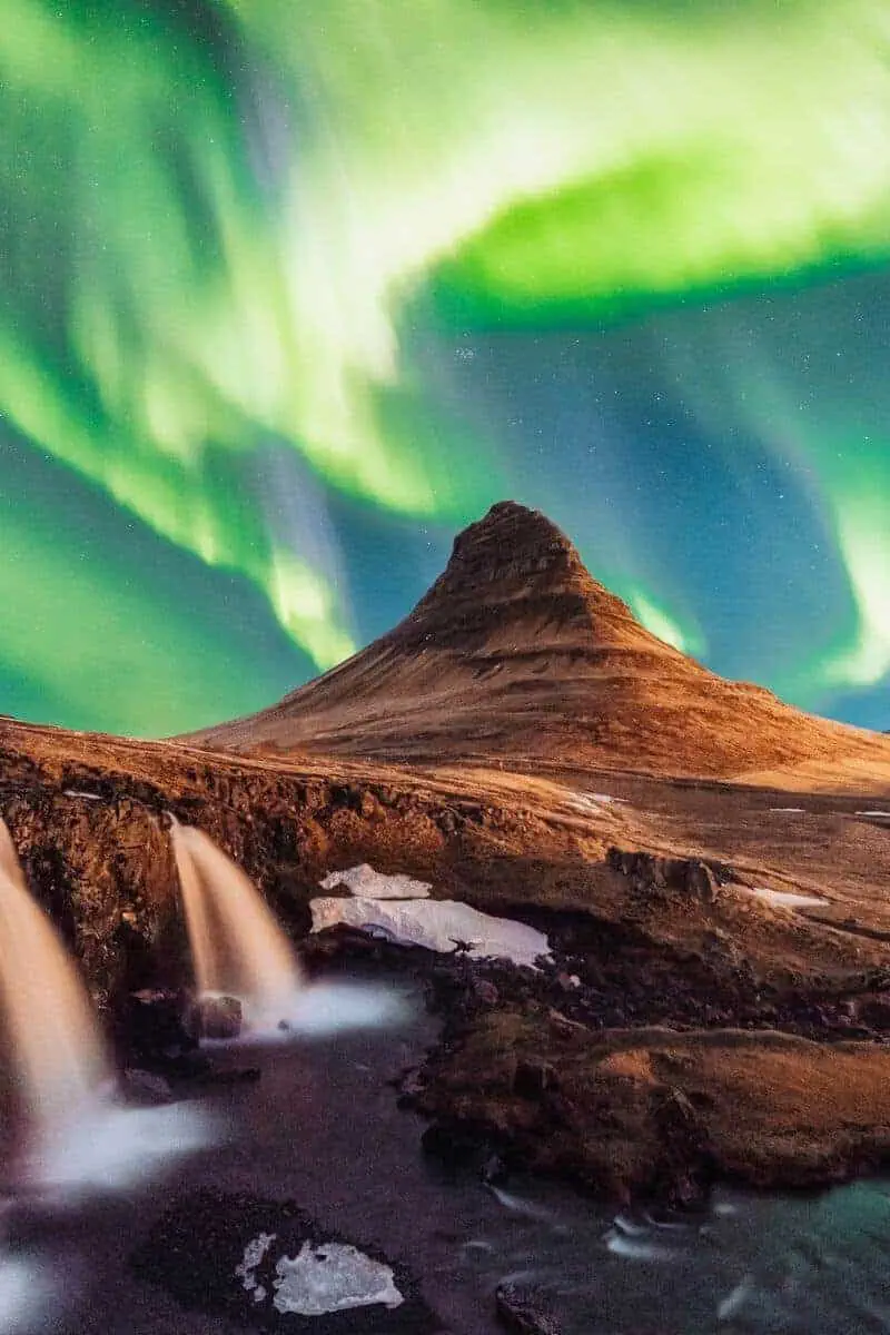 The northern lights in Iceland above a rugged landscape with waterfalls