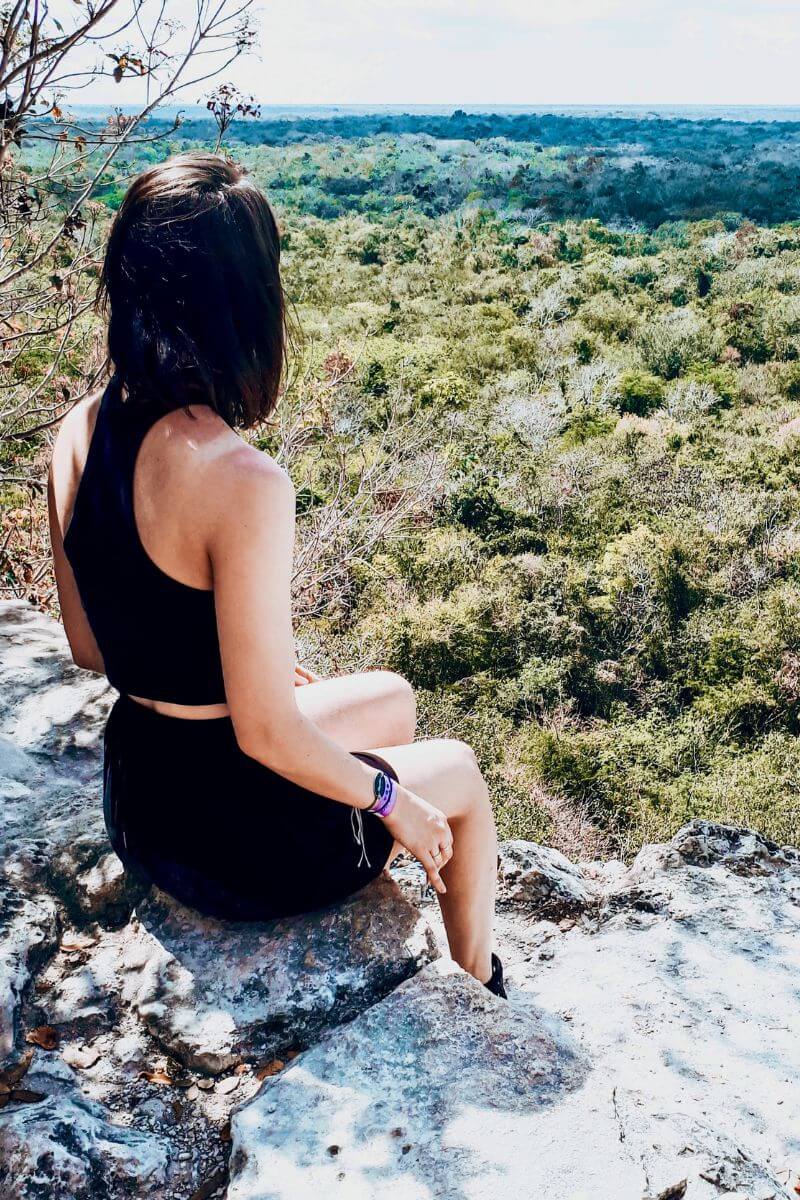 Hannah sitting at the top of a pyramid overlooking a tropical forest in Coba, Mexico