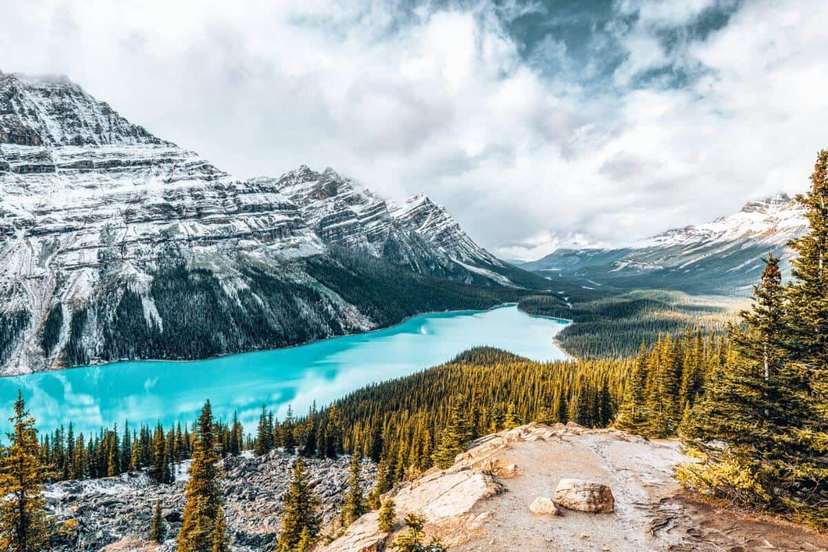A brilliant blue lake surrounded by snowy mountains and pine trees in Canada