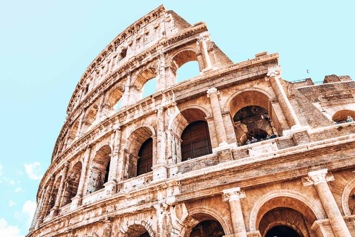 The ancient, golden coloured colosseum in Rome on a sunny day