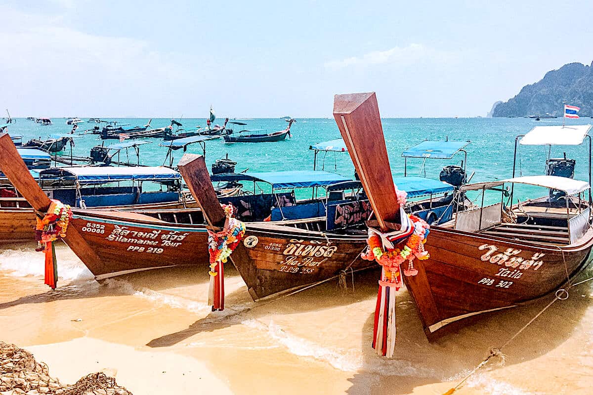Close up of three traditional wooden longtail boats on the beach in Thailand