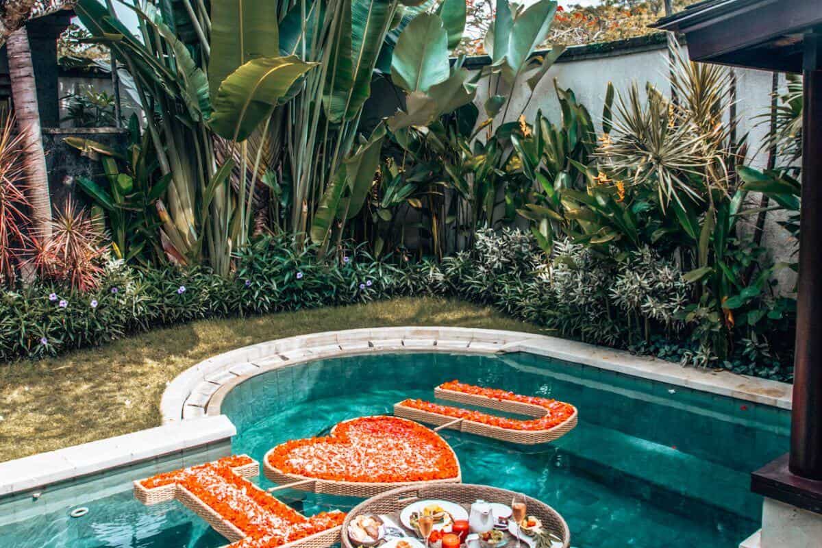 A private pool in a villa in Bali with a floating breakfast basket and petals that say 'I heart U'
