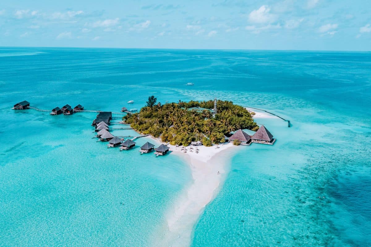 A tiny tropical island in the middle of the ocean in the Maldives with overwater villas