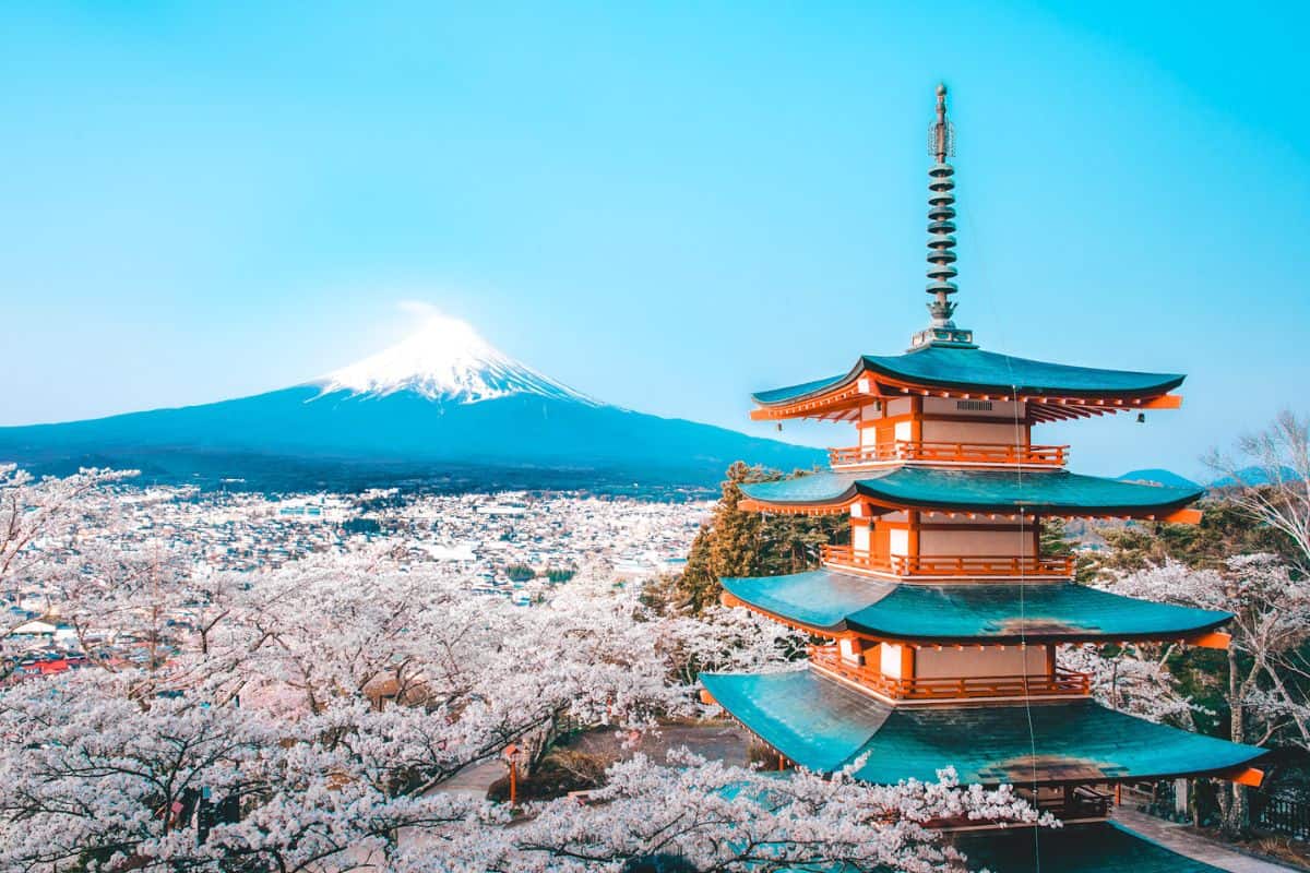 A traditional temple in Japan overlooking cherry blossoms and Mount Fuji in the background