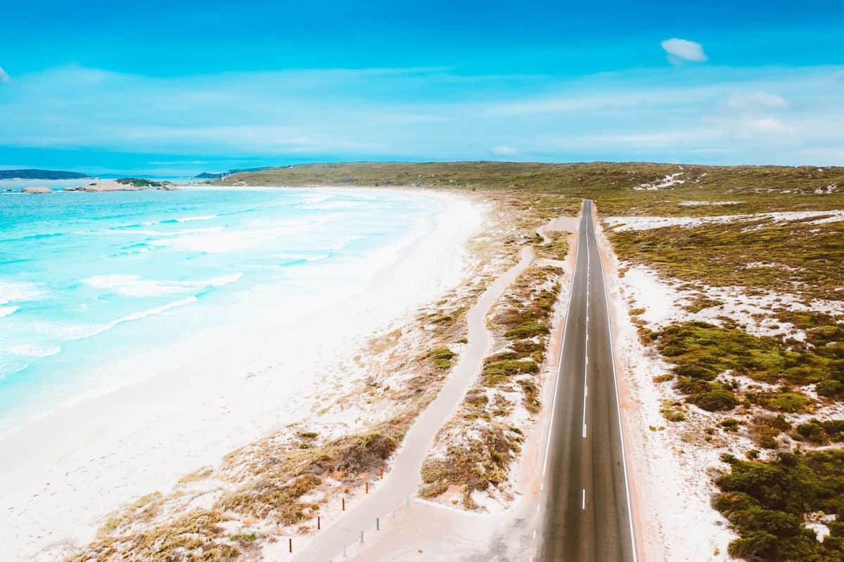 An aerial view of a straight road alongside the beach in a remote part of Australia
