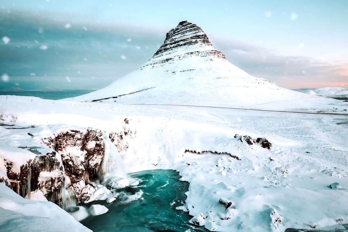 A picturesque waterfall and mountain in Iceland covered in heavy snow