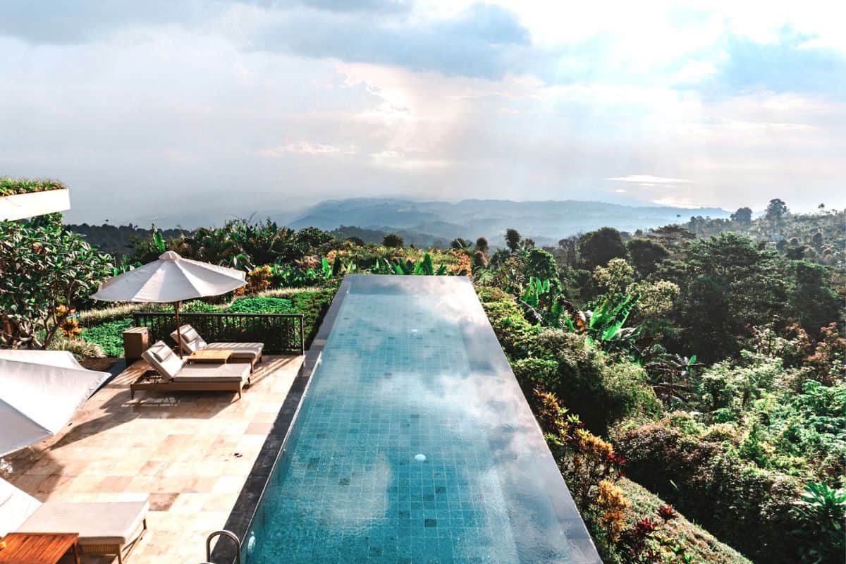An infinity pool and loungers set above jungle scenery at a resort in Munduk, Bali