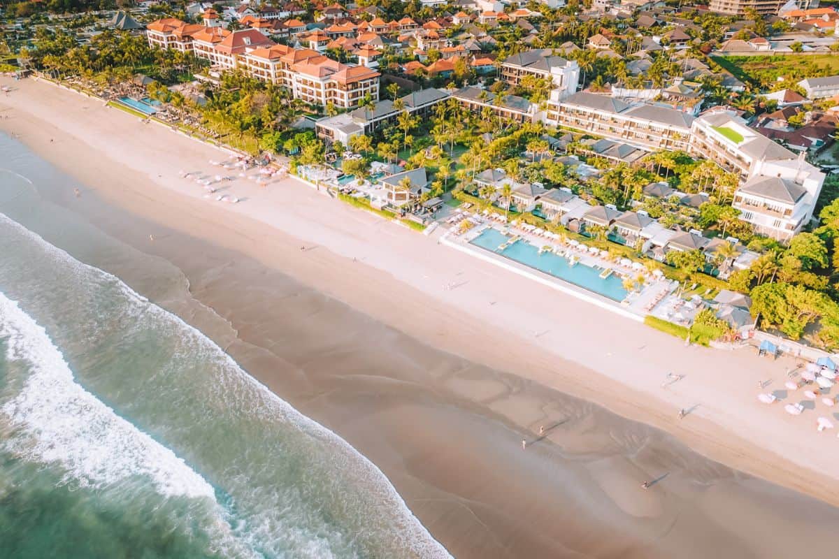 An aerial view of a luxury resort set on a sweeping golden beach in Seminyak, Bali