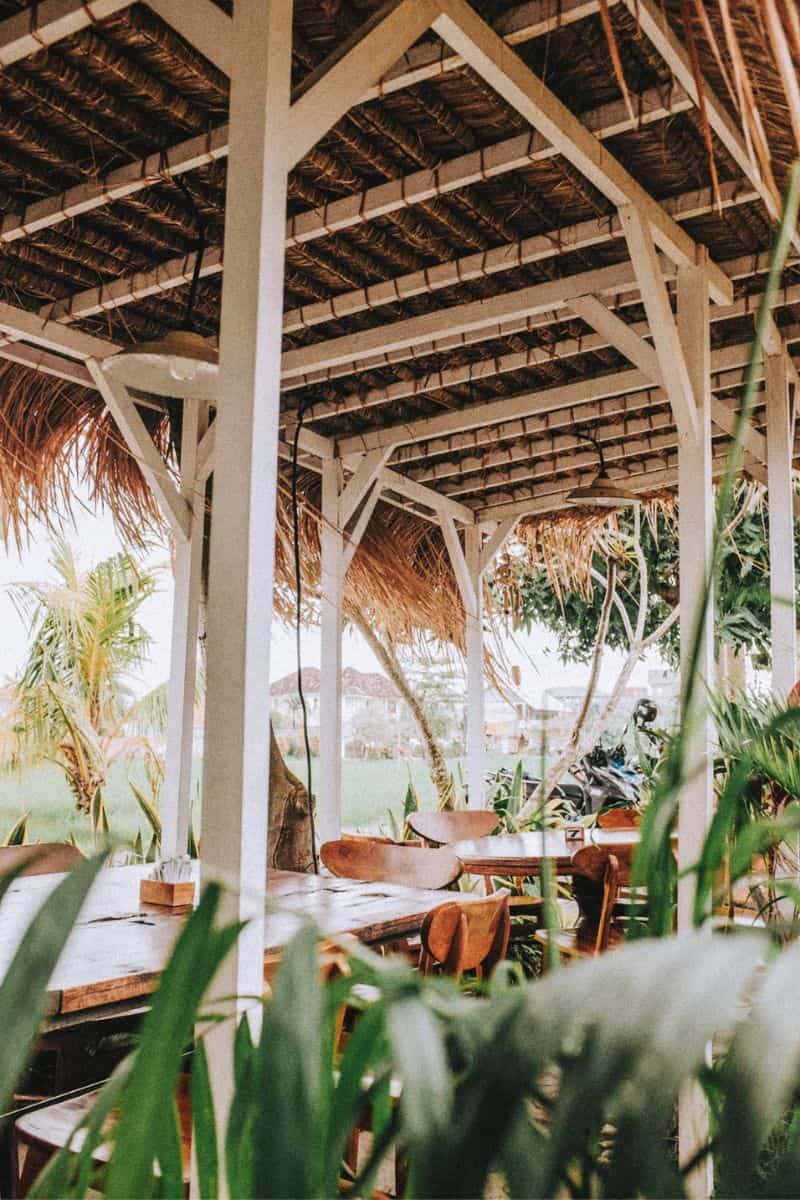 A semi-open rustic-style cafe in Bali overlooking rice fields