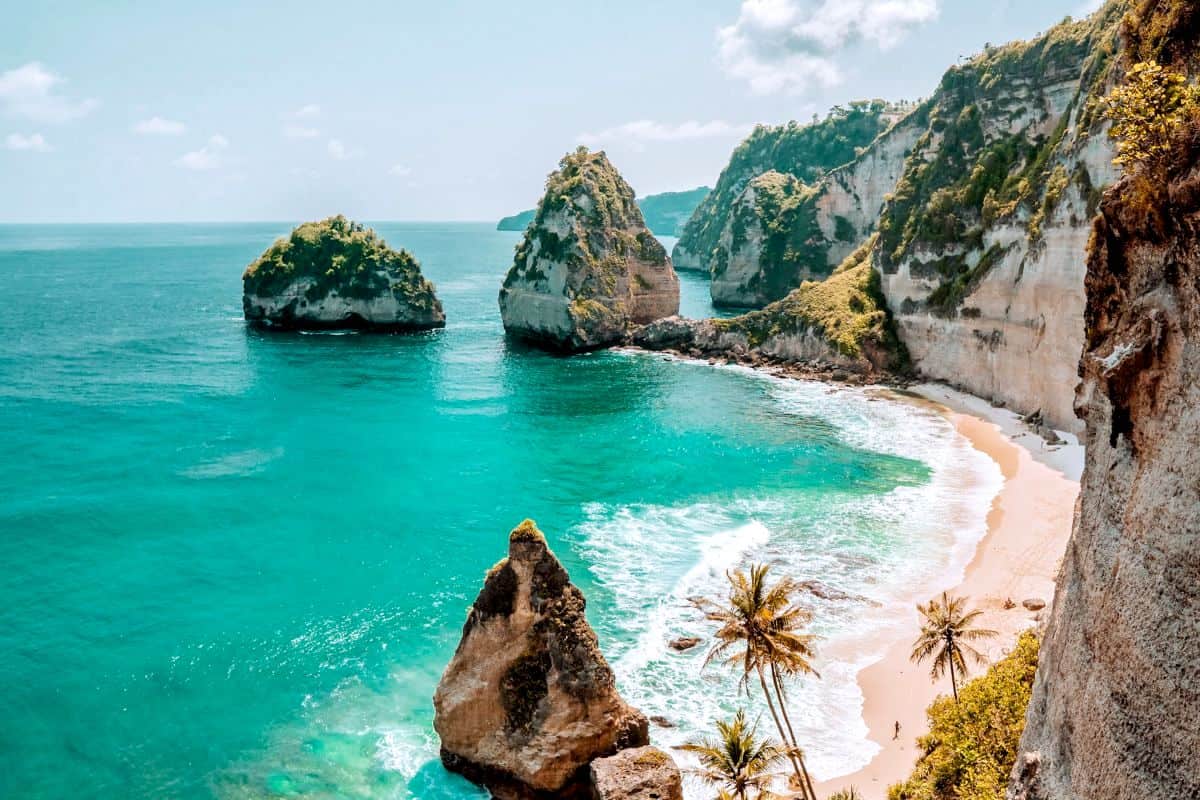 A rugged and secluded white-sand beach at the bottom of a cliff on Nusa Penida island near Bali