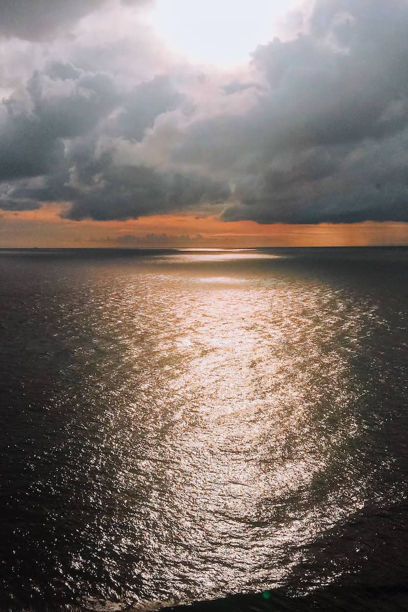 A sun setting over still, dark ocean at Uluwatu in Bali