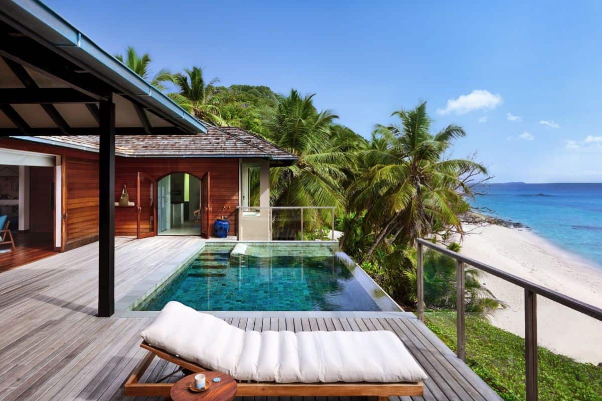 A luxury villa in the Seychelles with a private pool and sun loungers overlooking a tropical beach