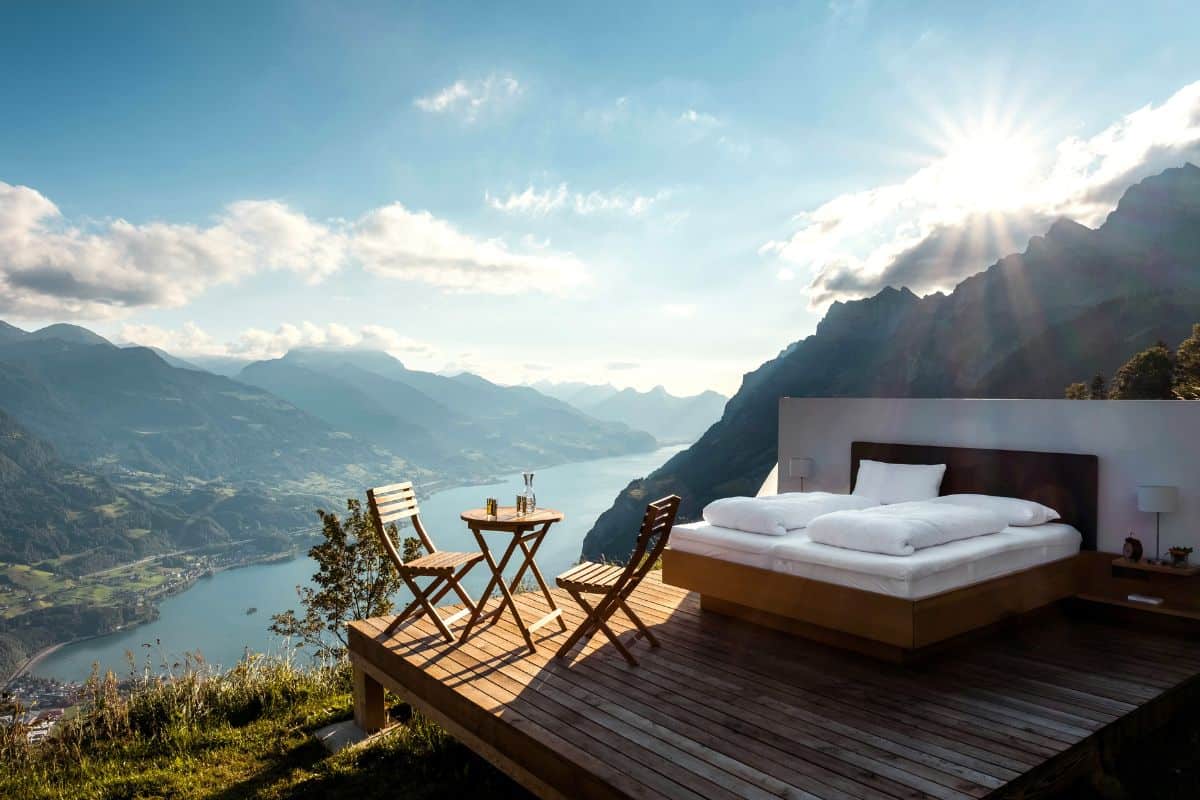 A bucket list open-air hotel concept with a bed on a platform in the mountains