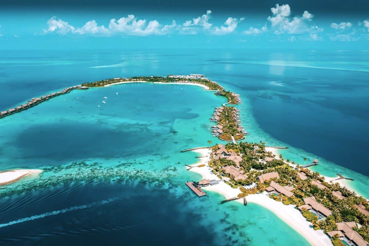 An aerial view of an expansive private island resort in the Maldives, surrounded by turquoise water