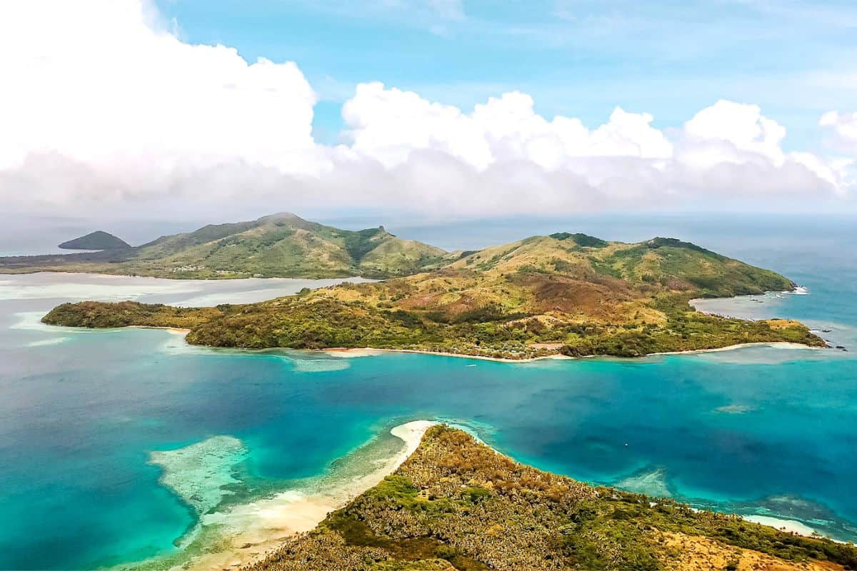 An aerial view of several hilly, tropical islands in Fiji, surrounded by crystal waters