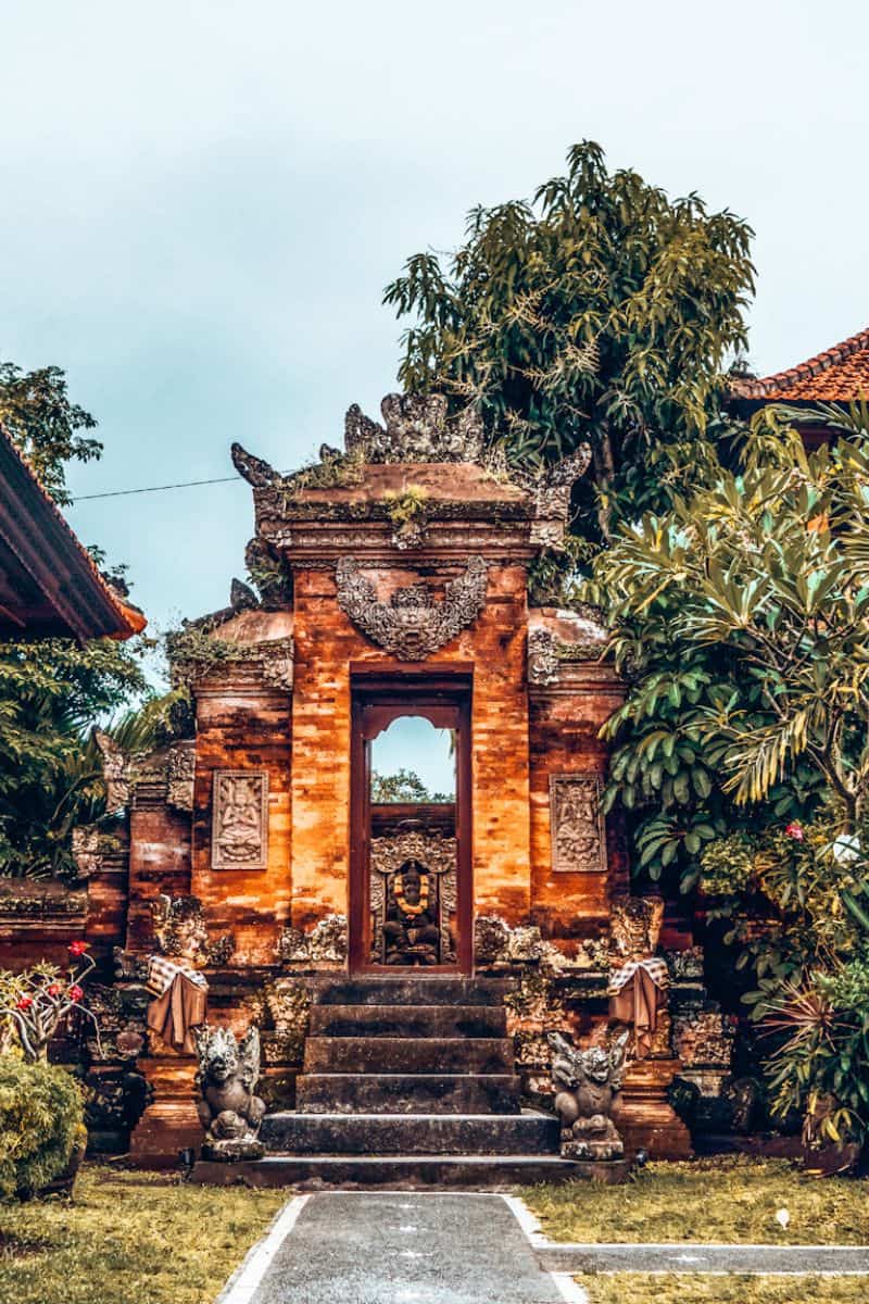 An ornate and traditional Balinese temple and gate in Ubud, surrounded by greenery