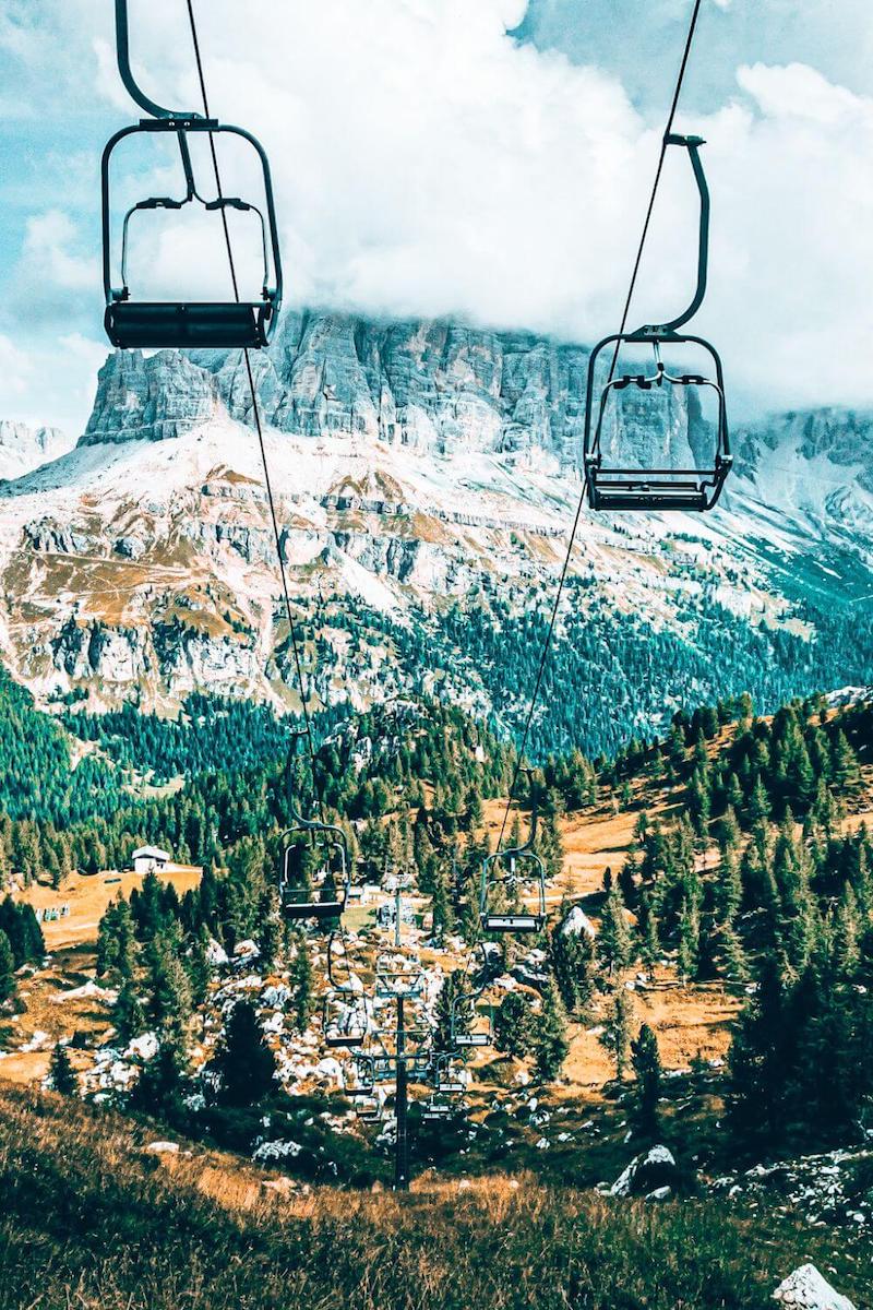 View from a chairlift looking down at a small resort town at the foot of a snowy mountain