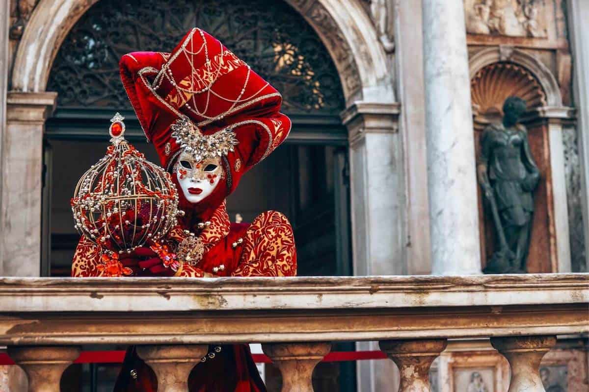 A woman wearing an ornate red costume and mask for Venice Carnival