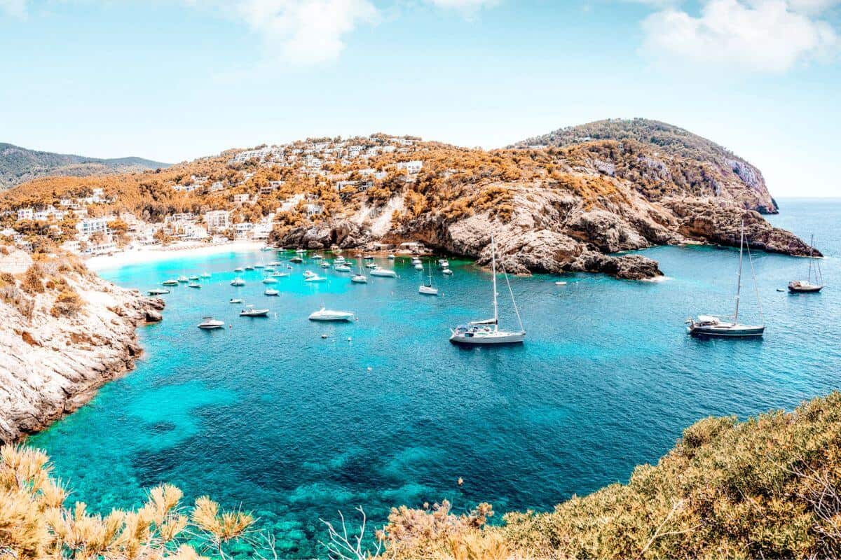 A pretty cove with teal waters and small boats in Spain's Balearic Islands