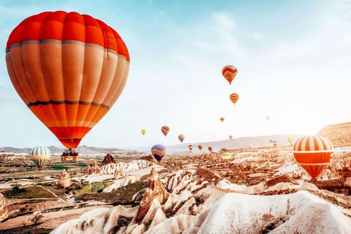 Multi-coloured hot air balloons taking flight above a rocky landscape in Cappadocia, Turkey