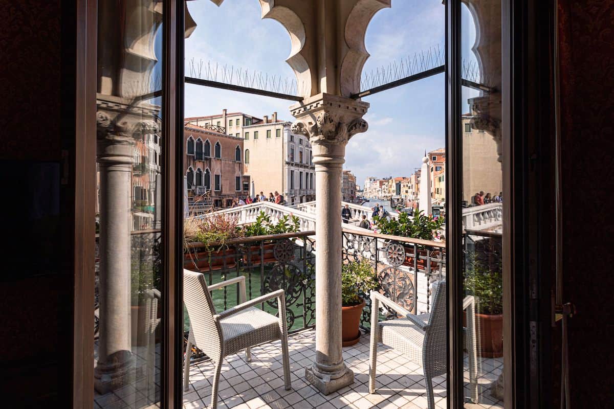 A view through patio doors onto a romantic private terrace next to a canal in Venice