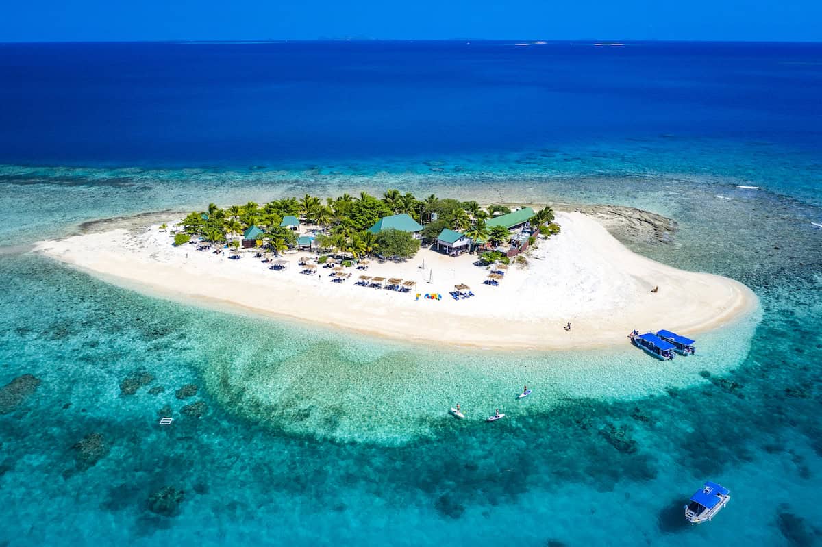 An aerial view of a tiny white-sand tropical island in Fiji