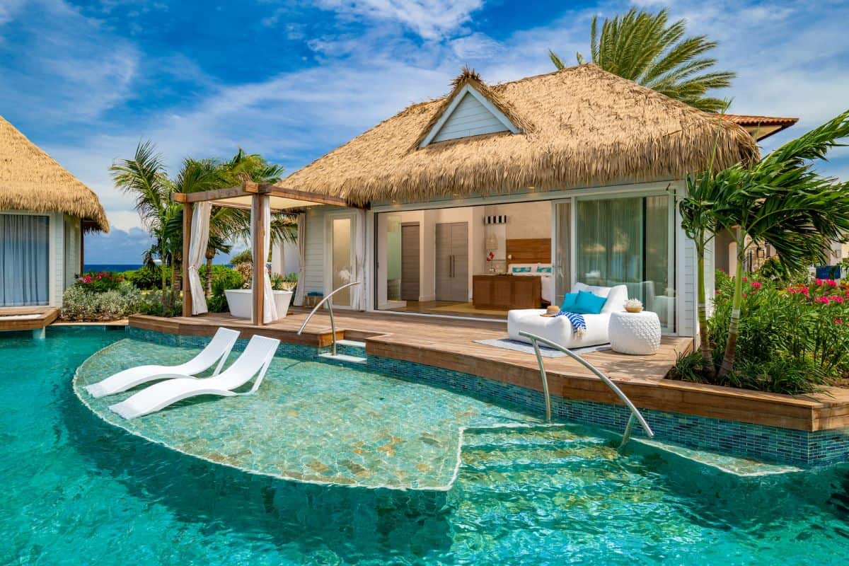 A romantic thatch roof villa by a pool at a resort in the Caribbean