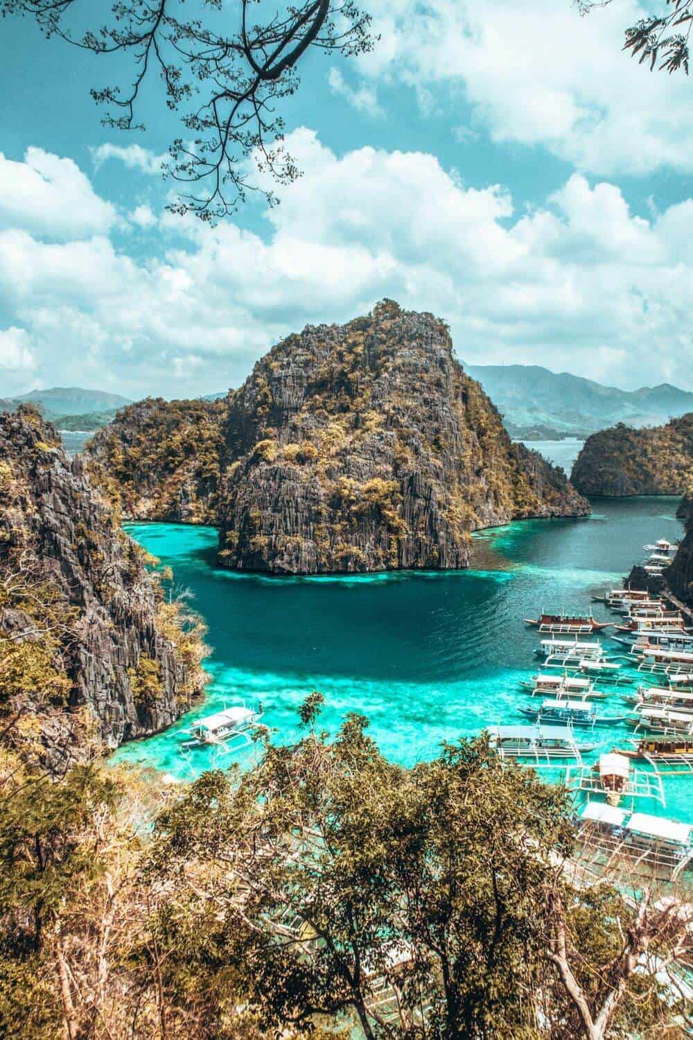 Traditional boats and mountainous limestone mountains in a secluded turquoise bay in the Philippines