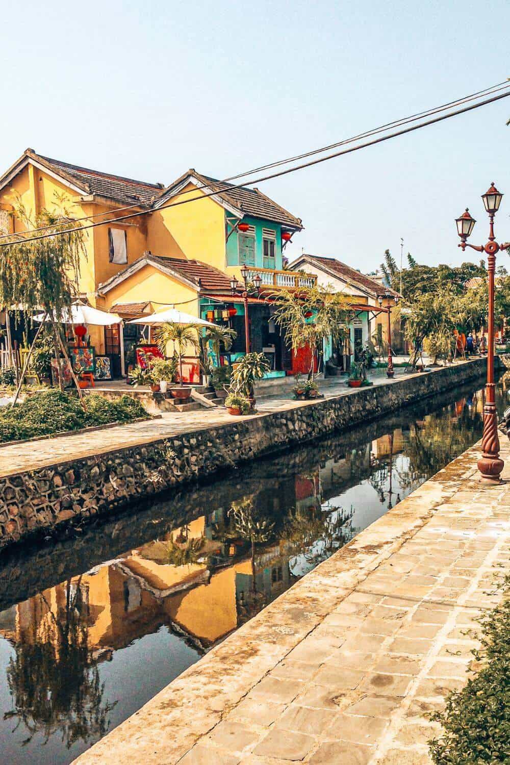 A small and picturesque canal in front of traditional colourful buildings in Hoi An