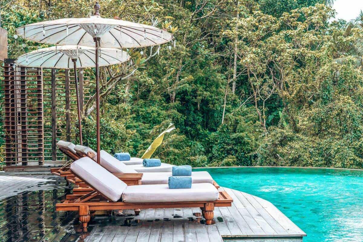 Several sun loungers beside a pool in a jungle hotel in Bali
