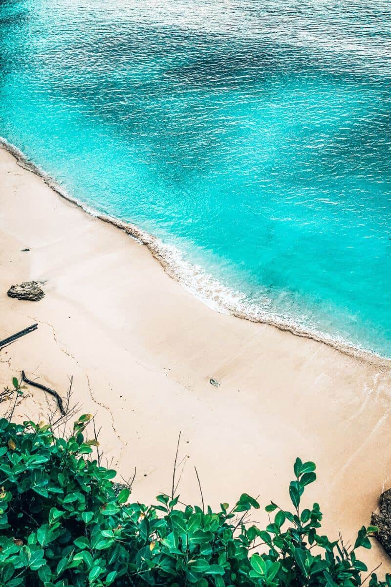 A clean white sandy beach with turquoise water in Uluwatu, Bali