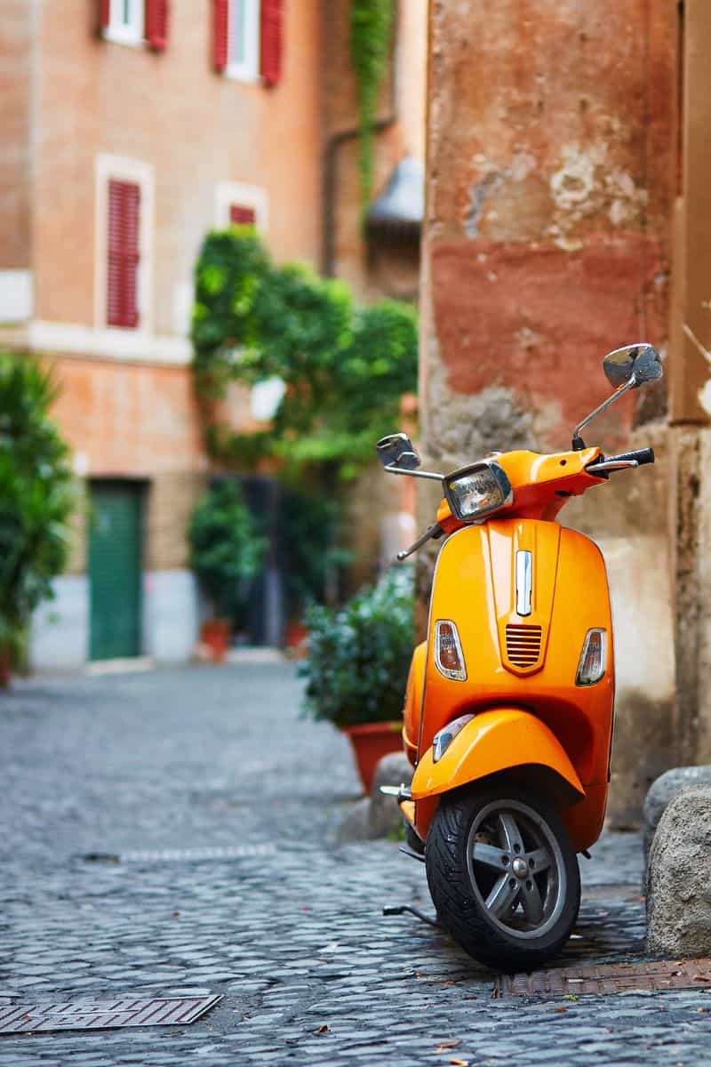 An orange moped in a quiet street in Rome, Italy