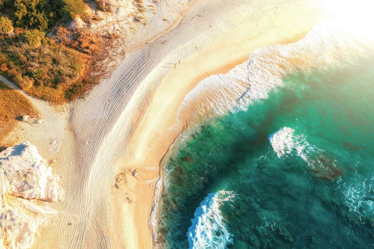 An aerial view of an empty, golden sand beach