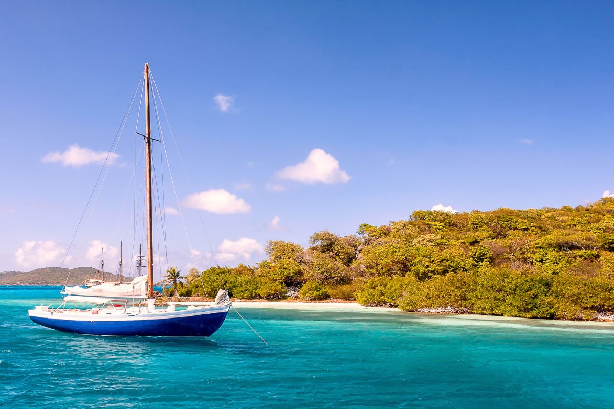 A traditional boat in turquoise water by an island in St Vincent in the Caribbean