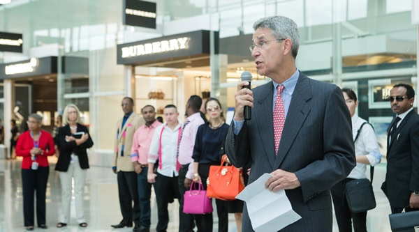 Businessman speaking into microphone at a busy airport terminal.