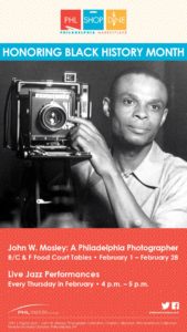 Black and white photo of a man holding a vintage camera, promoting Black History Month event.