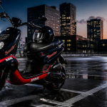 scooter booster 50cc noir rouge sur parking urbain