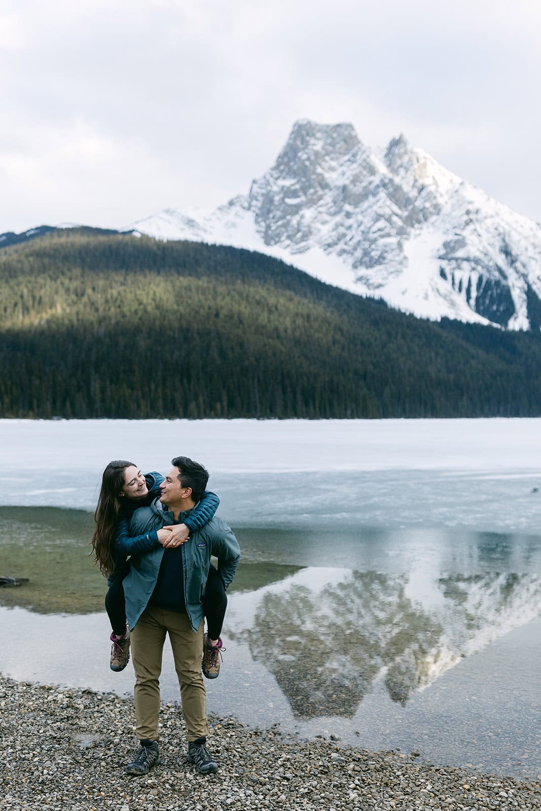 Banff engagement photographer photographing a couple walking along a lakeshore in the Rockies