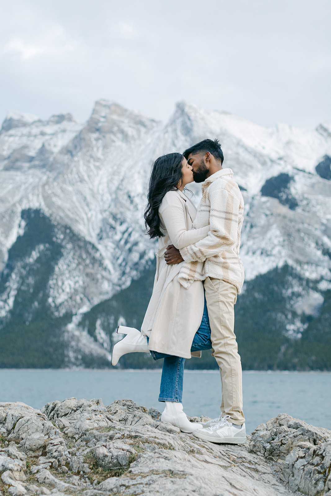 Banff engagement photographer documenting a couple embracing with snow-capped peaks behind them