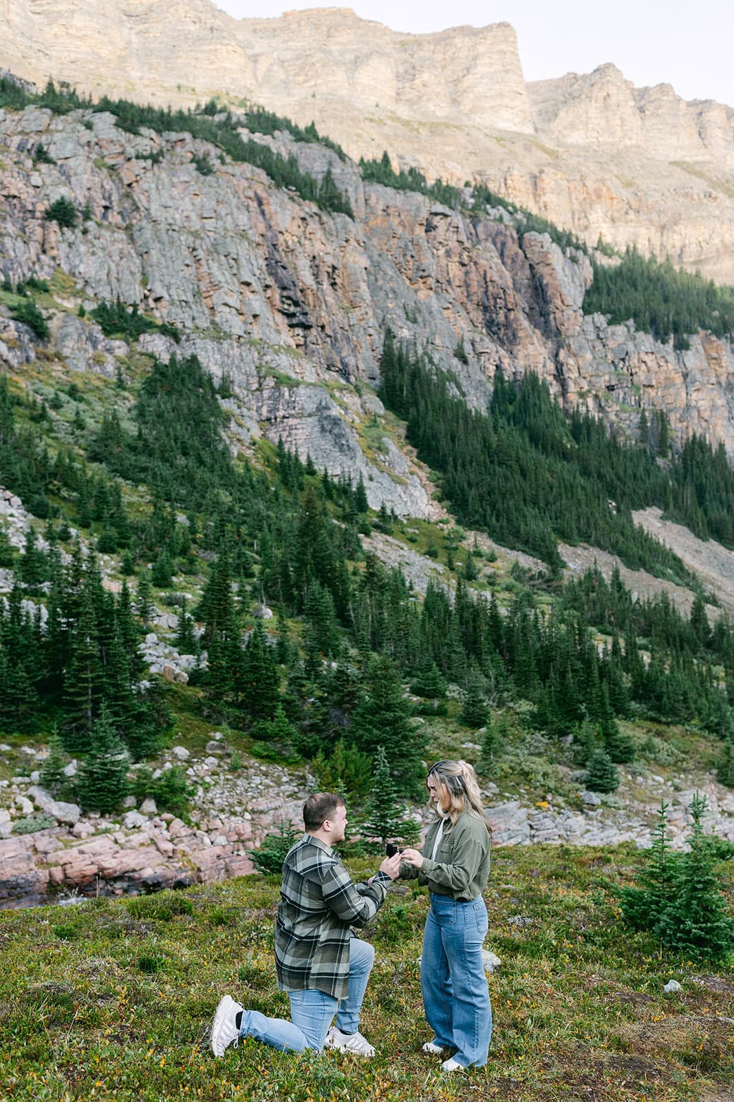 Romantic heli proposal on a mountaintop in Banff with sweeping alpine views and dramatic peaks