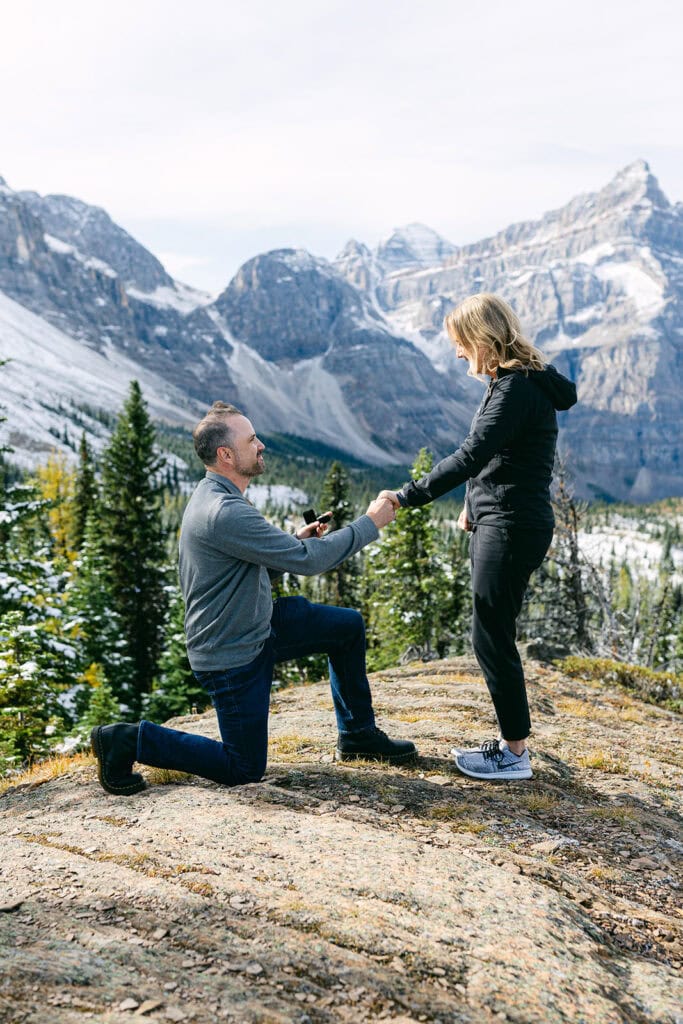 Alpine Helicopters Banff proposal flight with snow-dusted mountain peaks and clear ground below in the Canadian Rockies