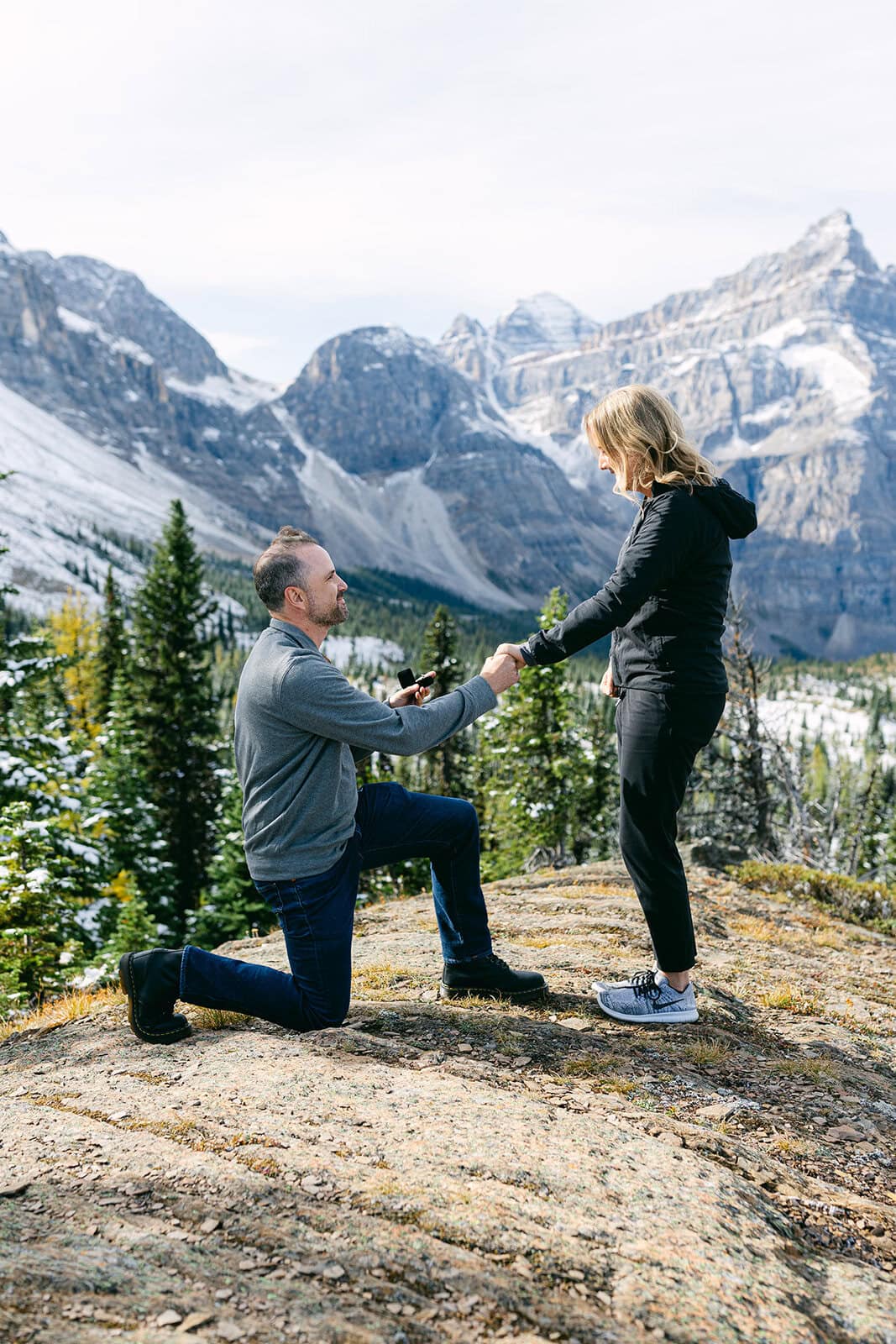 Alpine Helicopters Banff proposal flight with snow-dusted mountain peaks and clear ground below in the Canadian Rockies