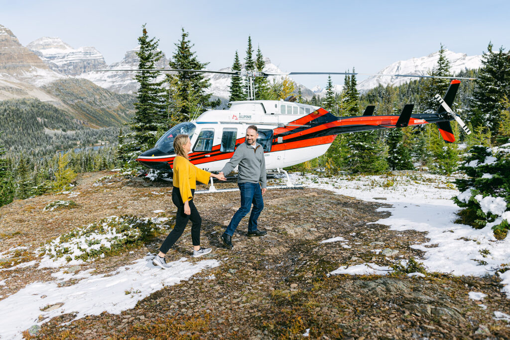 A couple getting engaged during an Alpine Heli flight over rugged mountains with patchy snow on high elevations