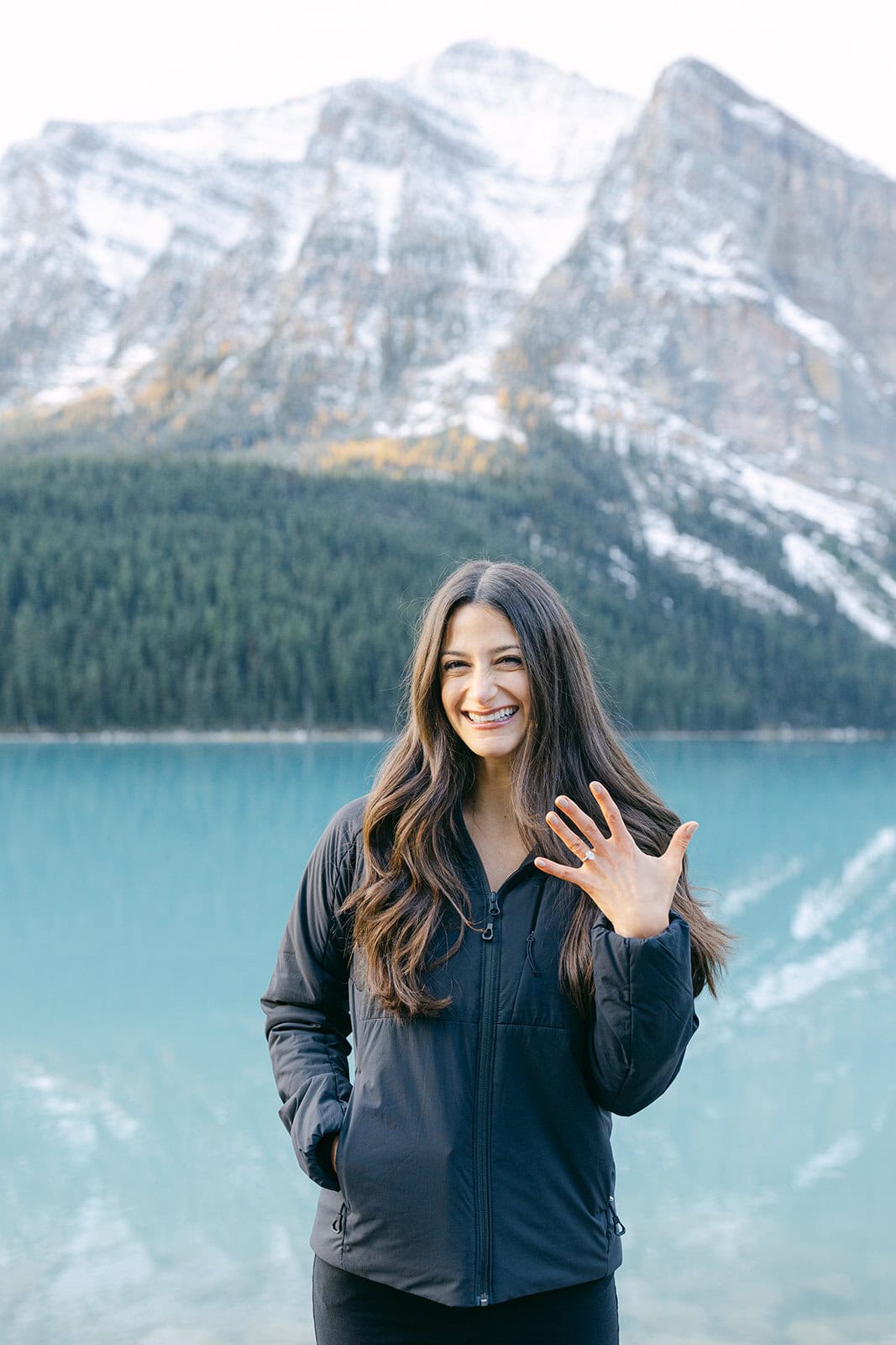 Surprise Lake Louise proposal with turquoise water, autumn trees, and snow on the mountain ridges